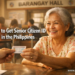 A Filipino senior citizen receiving her laminated Senior Citizen ID card from a municipal hall employee.