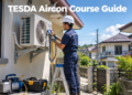 A Filipino aircon technician services a split-type air conditioner's outdoor unit as part of TESDA RAC Servicing training.